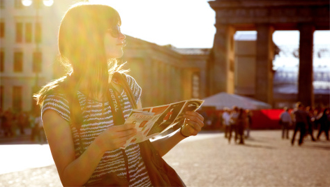 A woman in sunglasses with a map in a European cityscape