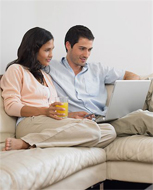 Couple sitting on a couch, using a laptop
