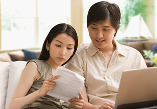 Un jeune couple passe en revue ses documents de budget et ouvre une session en ligne pour consulter l'outil Sélecteur de CPG afin d'évaluer son programme d'épargne.