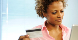 Une jeune femme avec sa carte de crédit ouvrant une session en ligne pour vérifier des habitudes de dépenses.