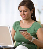 A smiling woman enters her credit card information on the computer