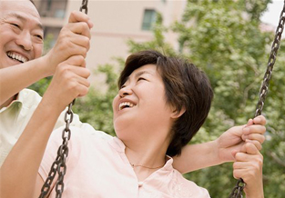 Retired man pushing his wife on a swing.