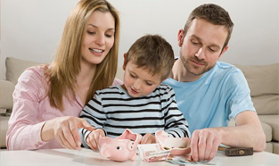 A young couple sitting at the kitchen table with their son breaking open a piggy bank with a small hammer.