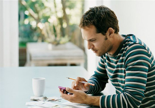 Young man sitting at the kitchen table using a calculator to find out how much a TFSA could help him save.