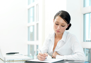 Young woman sitting at a table with her laptop open as she reviews how to use her TFSAs to plan ahead.